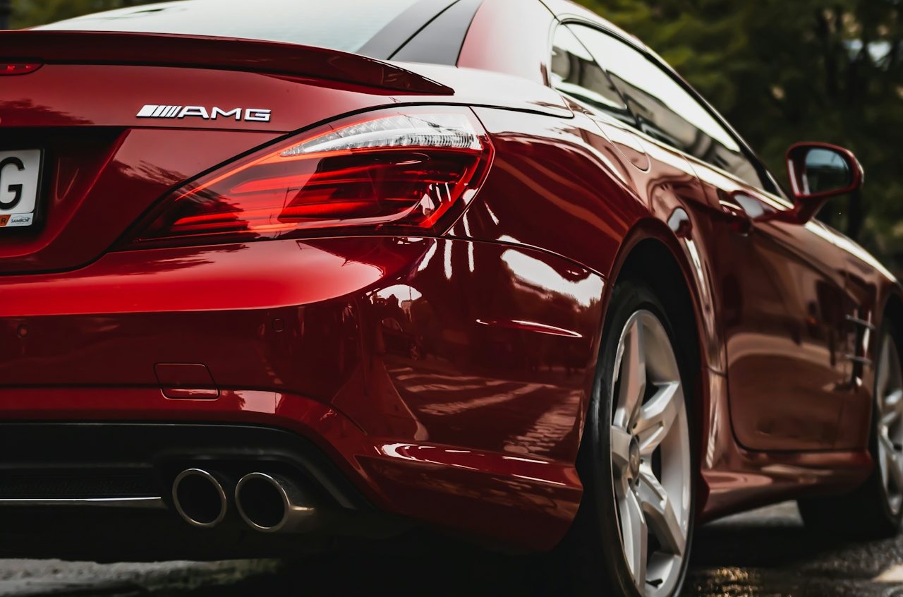 Roter Sportwagen Mercedes AMG mit glänzender Karosserie und doppelten Auspuffanlagen.